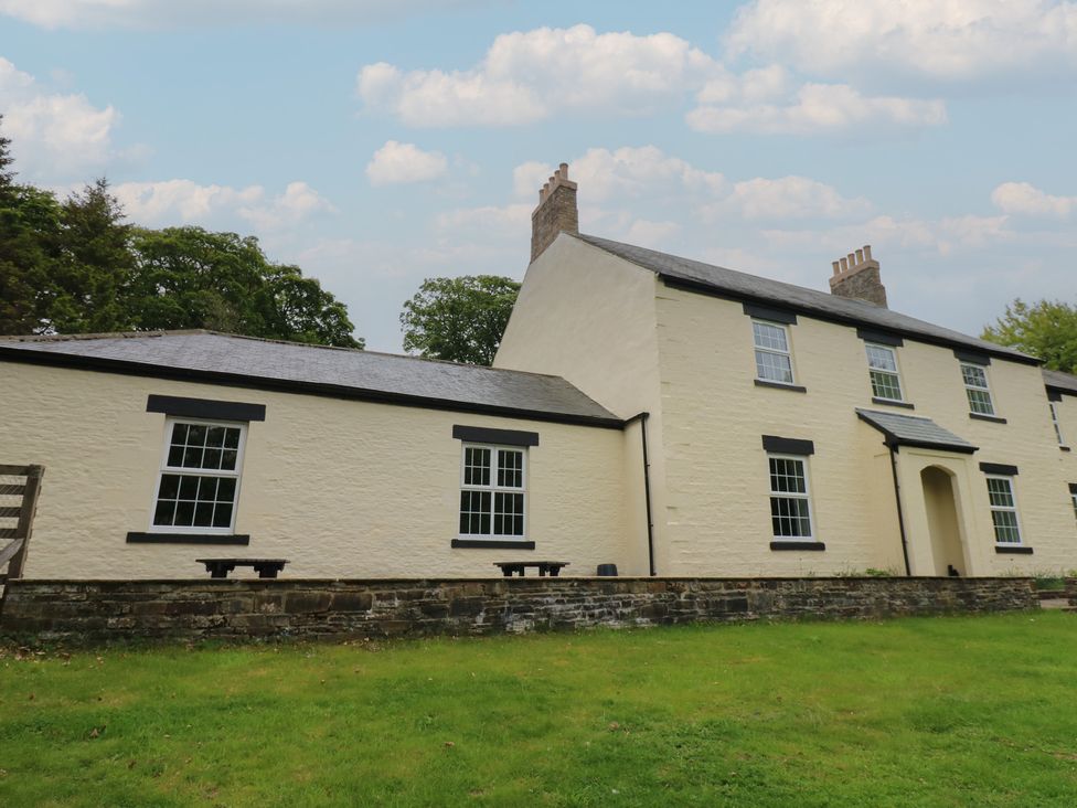A white stone house with black window frames and chimneys on a lawn at Nenthead House in Nenthead near Alston