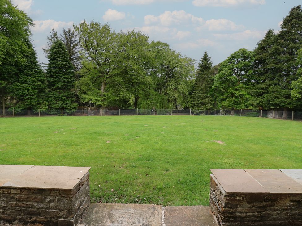 A lawn bordered by a low stone wall and trees at Nenthead House in Nenthead near Alston