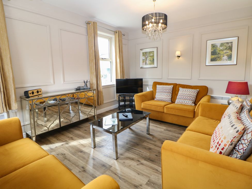 A living room with yellow sofas, a coffee table, and a television at Hardwick, Darley Moor near Two Dales