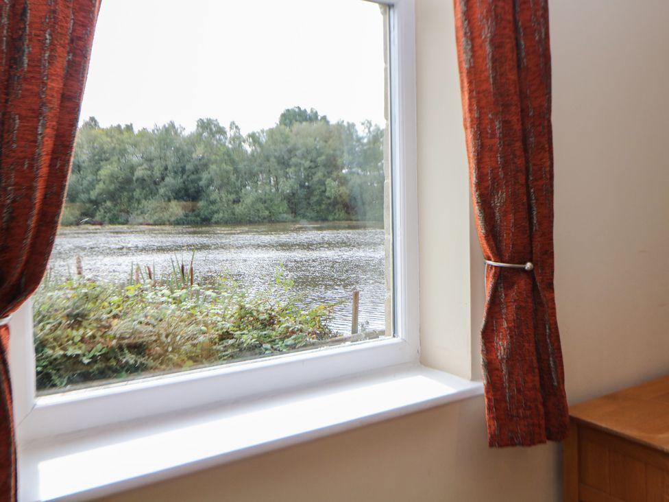 A window with open curtains showing a river view at Hardwick in Darley Moor near Two Dales