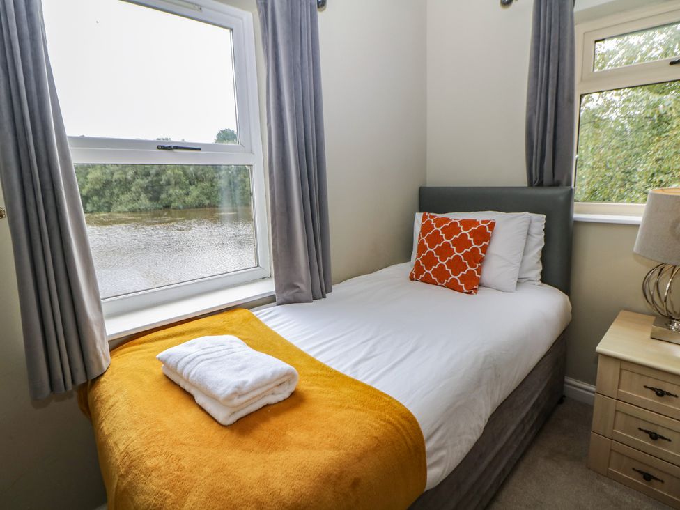 A bedroom with a single bed and a window overlooking a water view at Hardwick in Darley Moor near Two Dales