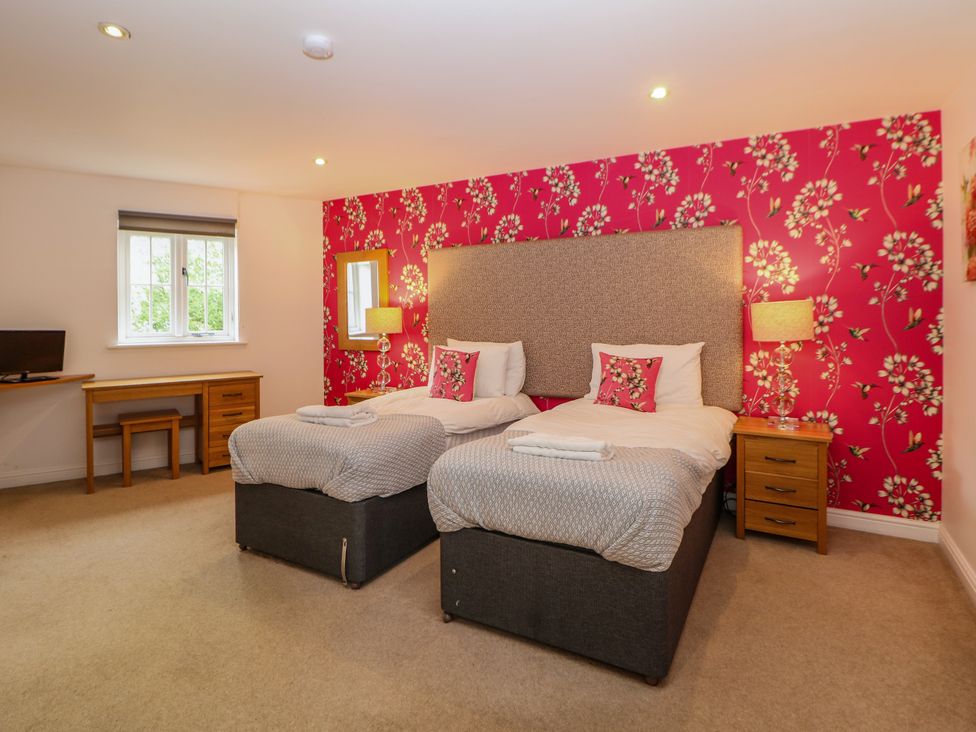 A bedroom with twin beds, a desk, and a television at Hartington in Darley Moor near Two Dales