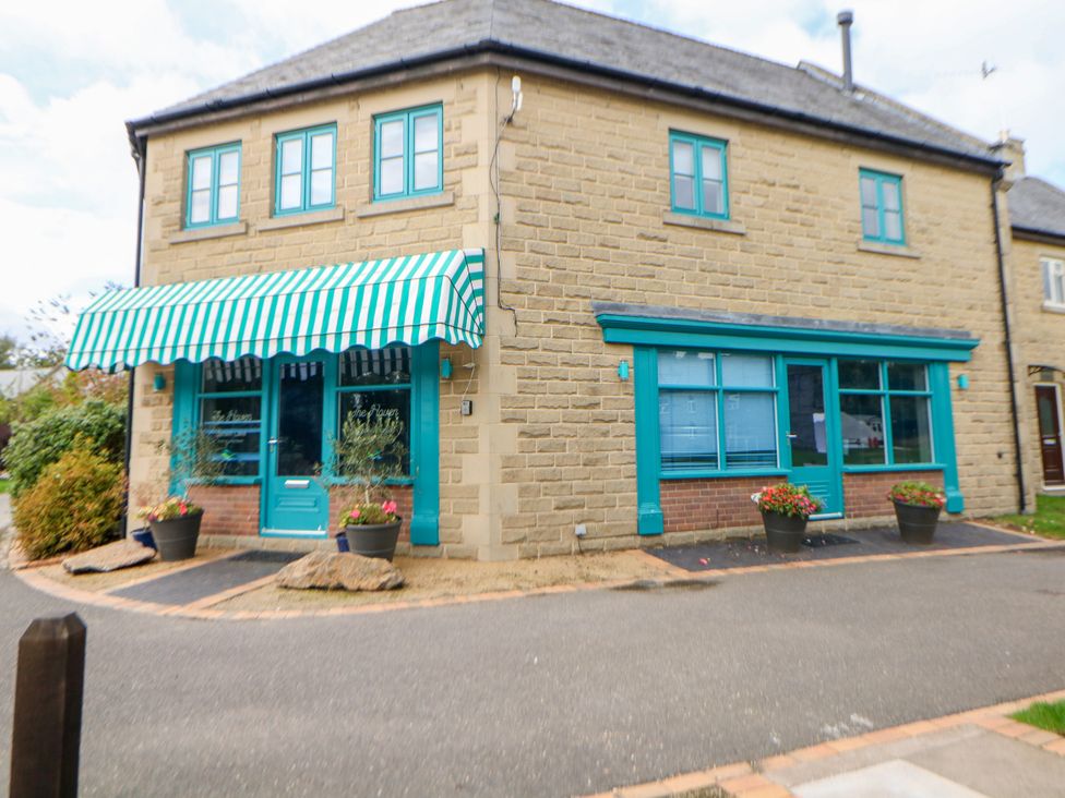 A building with a striped awning and planters at Riber in Darley Moor near Two Dales