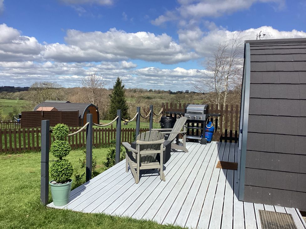 An outdoor area with a deck, chairs, and barbecue at Cherry Pod 2 Hookagate near Meole Brace