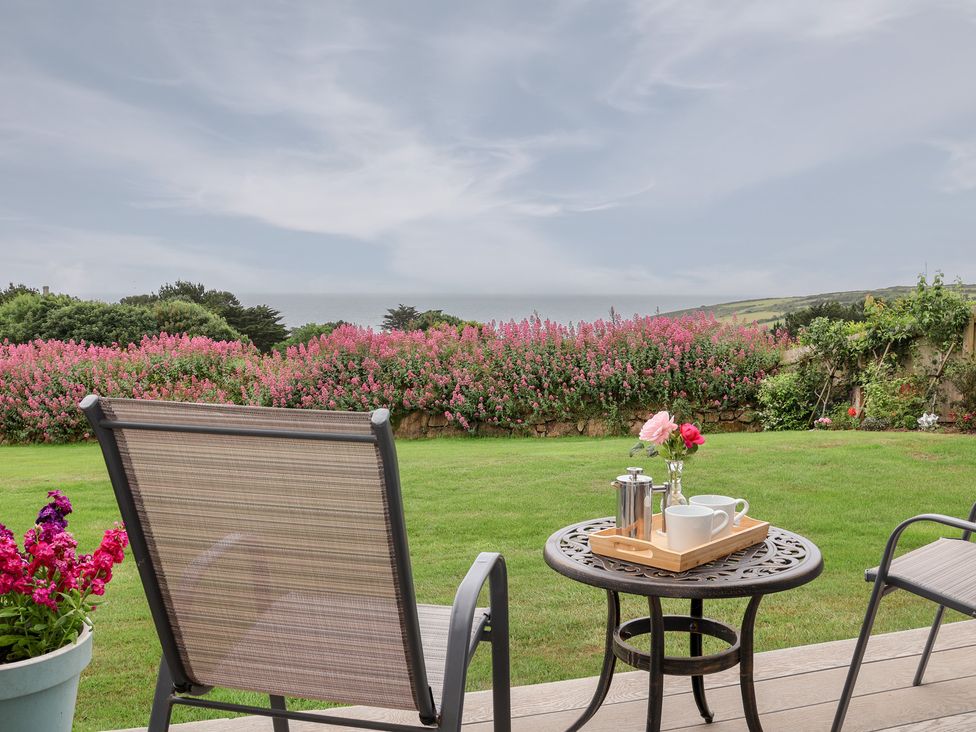 A garden with a table and chairs at Greenside Studio in Praa Sands