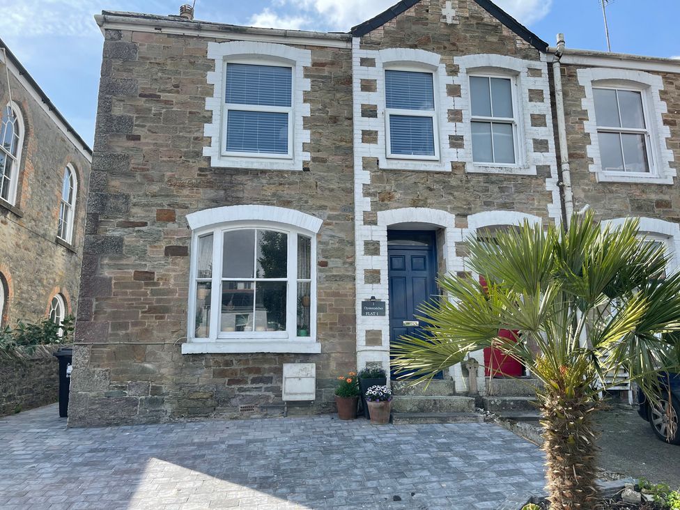 An outdoor view of a stone building with windows and a palm tree at The Oystercatcher in Falmouth
