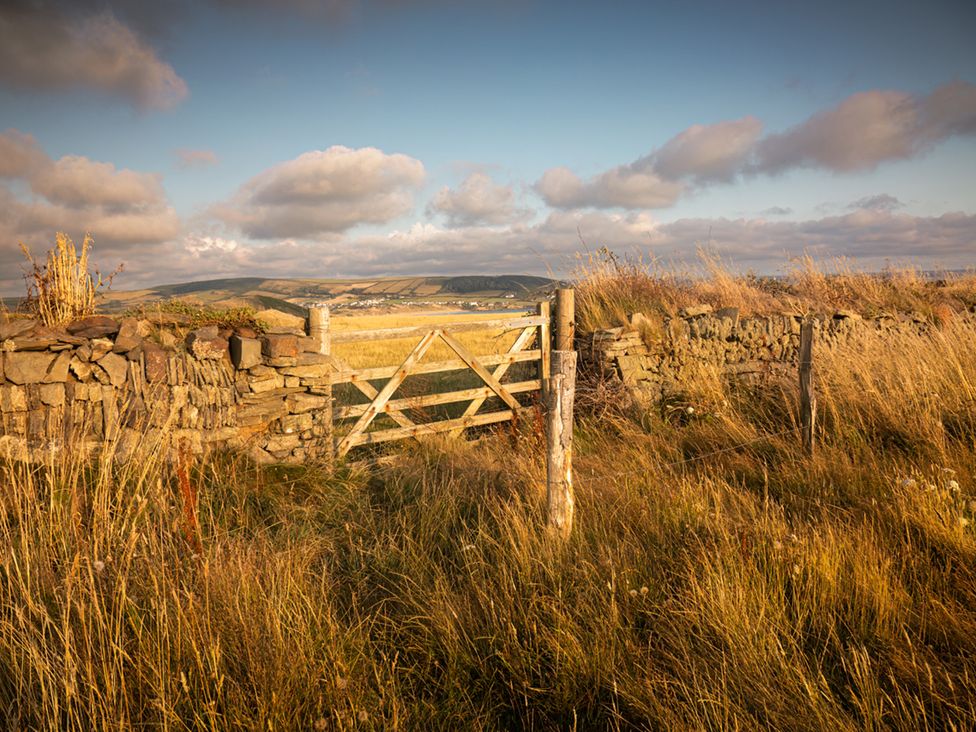 A gate near a stone wall in a grassy field at 2 Manleigh Park in Combe Martin