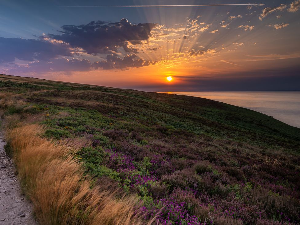 A sunset over the ocean viewed from a hillside at 2 Manleigh Park in Combe Martin