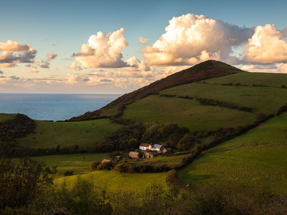 A landscape view of hills and a house near the ocean at 15 Manleigh Park Combe Martin