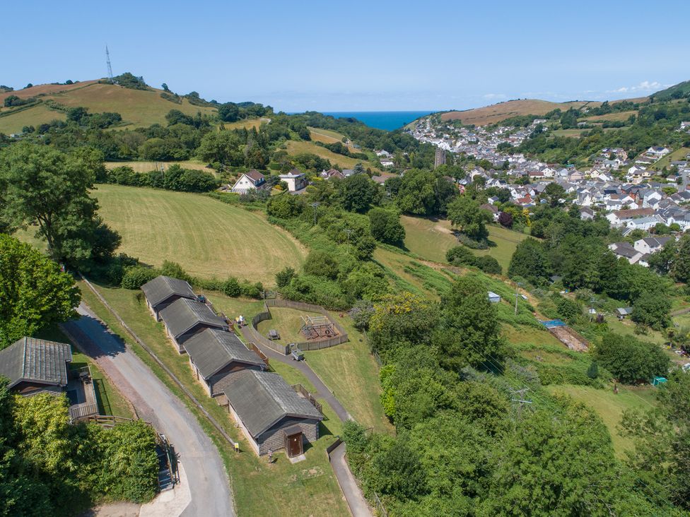 An outdoor view of fields and wooden cabins at 15 Manleigh Park in Combe Martin