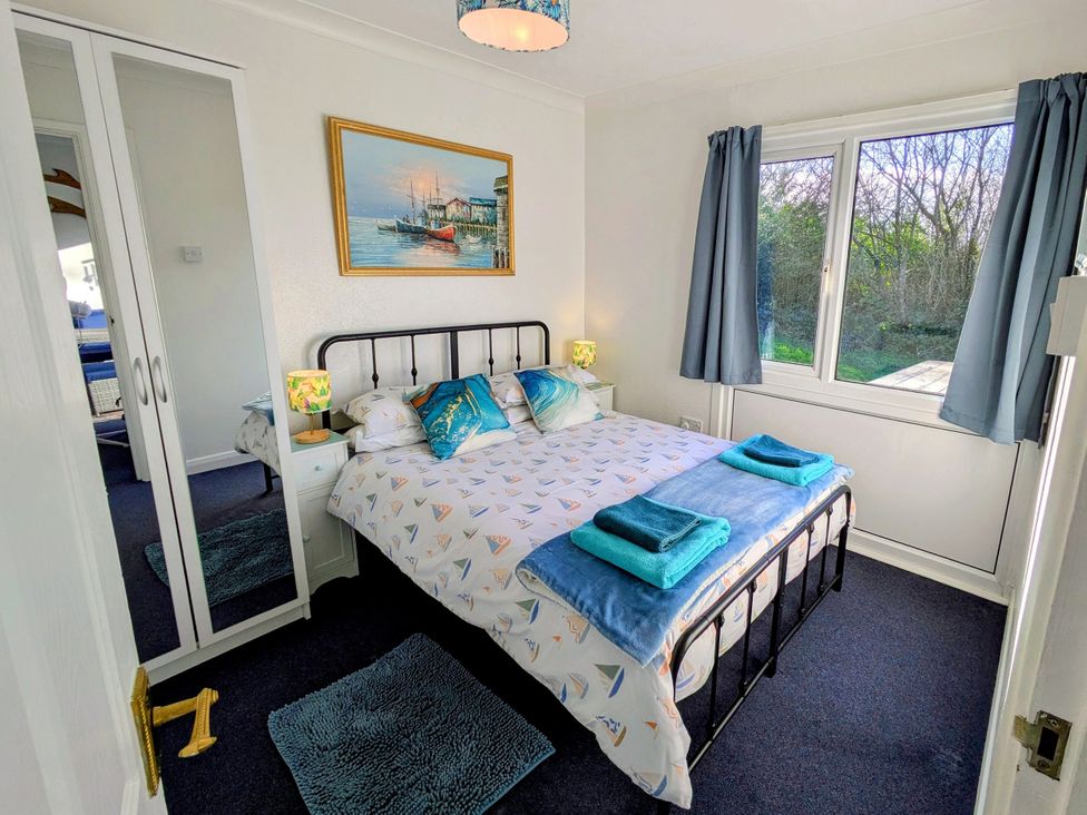A bedroom with a bed and mirror at 21 The Glade in Kilkhampton