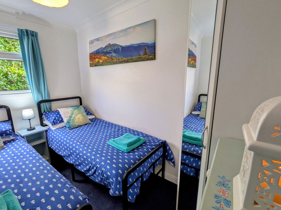 A bedroom with two beds and a bedside table at 21 The Glade in Kilkhampton