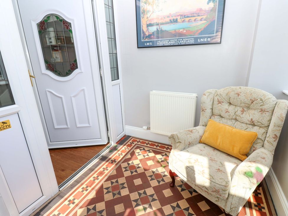 A hallway with a chair, radiator, and a door at Fern Lee in Carlisle