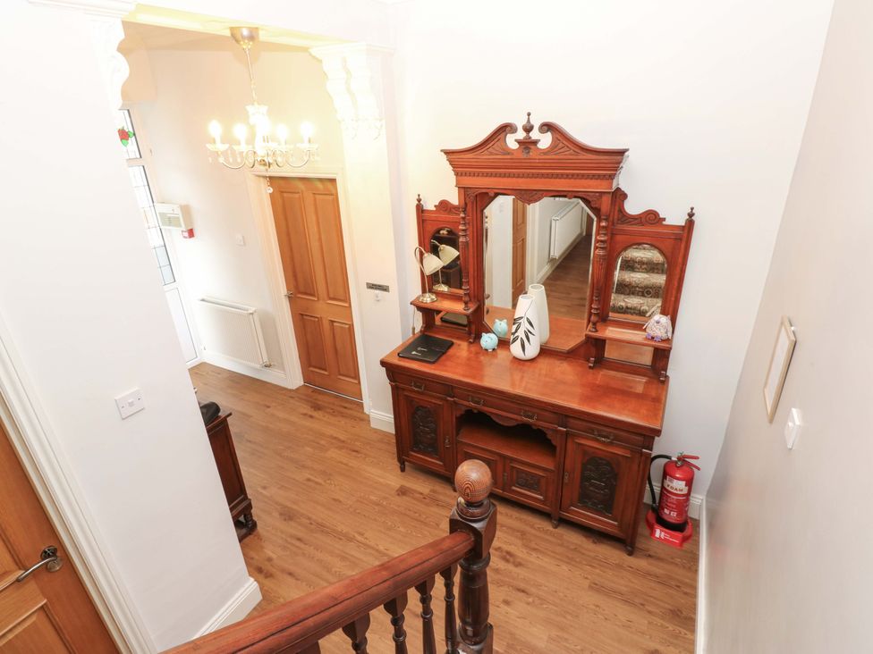 A hallway with a chandelier and wooden furniture at Fern Lee in Carlisle