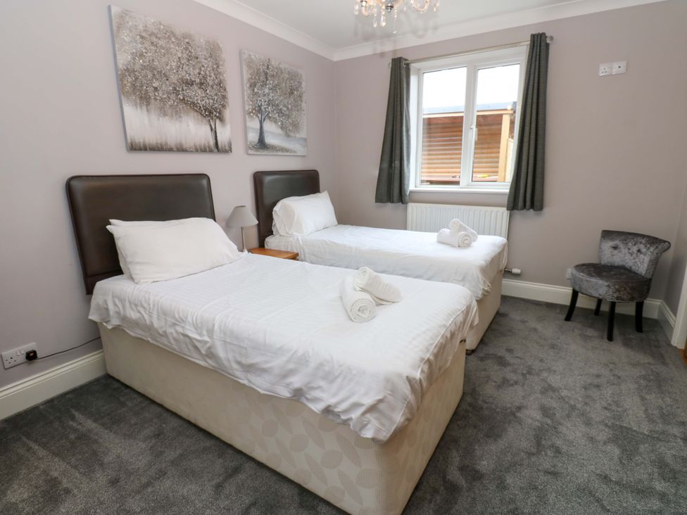 A bedroom with twin beds and a chair at Fern Lee in Carlisle