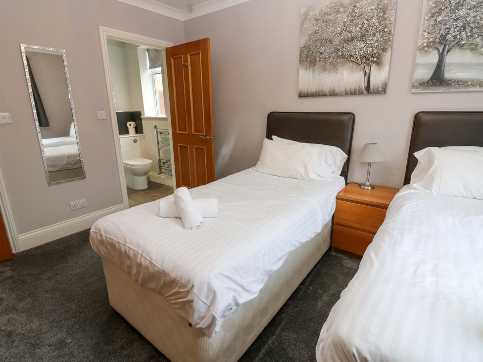 A bedroom with twin beds and a bathroom in view at Fern Lee in Carlisle