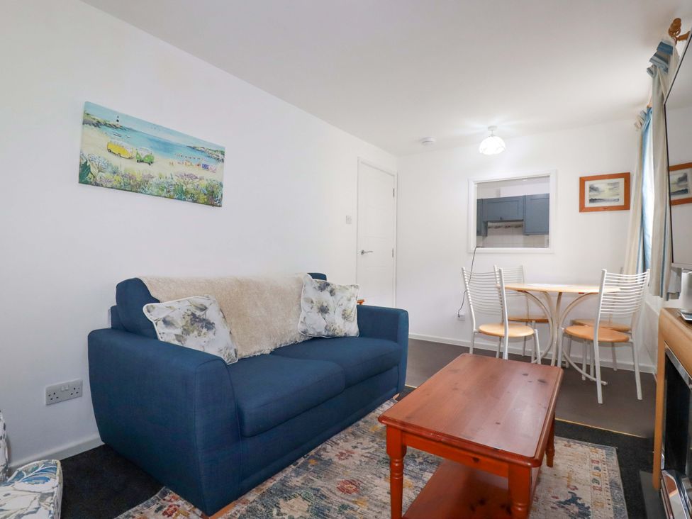 A living room with a blue sofa and a dining table at Seaside Apartment in Looe