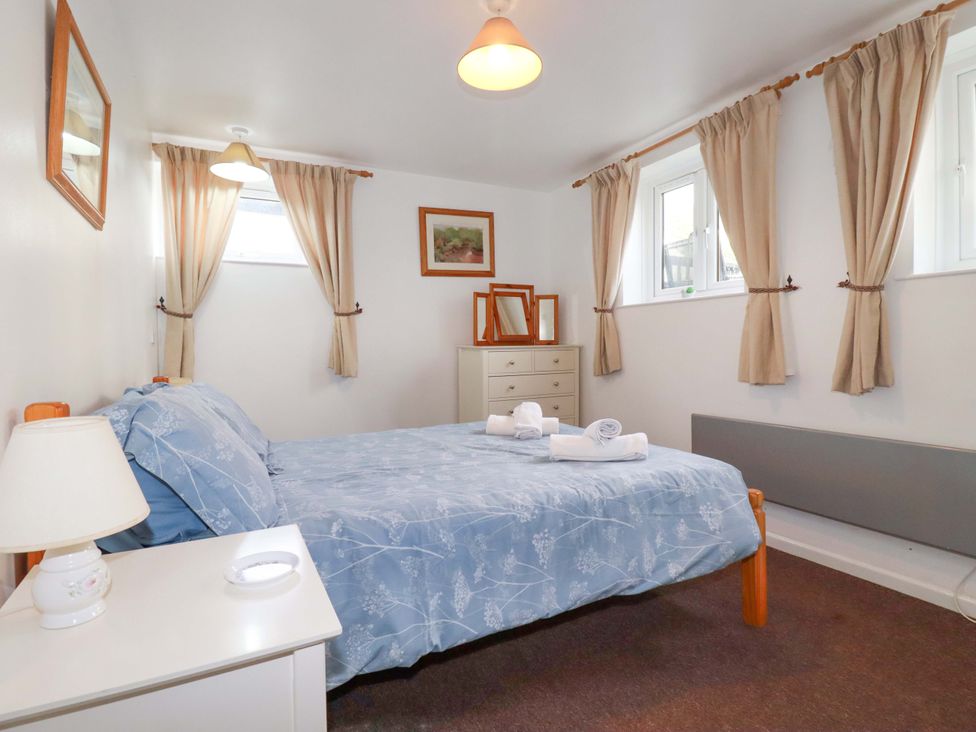 A bedroom with a bed and nightstand at Seaside Apartment in Looe