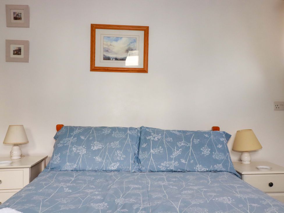 A bedroom with a bed and framed pictures at Seaside Apartment Looe