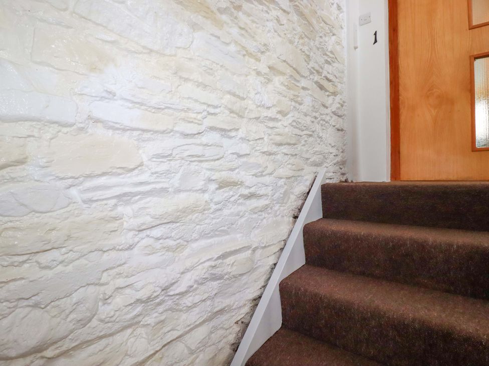 A staircase with a stone wall leading to a door at Seaside Apartment in Looe