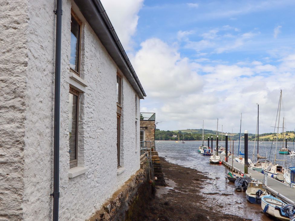A view of a building beside water with boats at Dolphin Cottage in Brixham