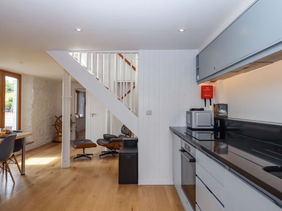 A kitchen with appliances and a staircase at Dolphin Cottage in Brixham