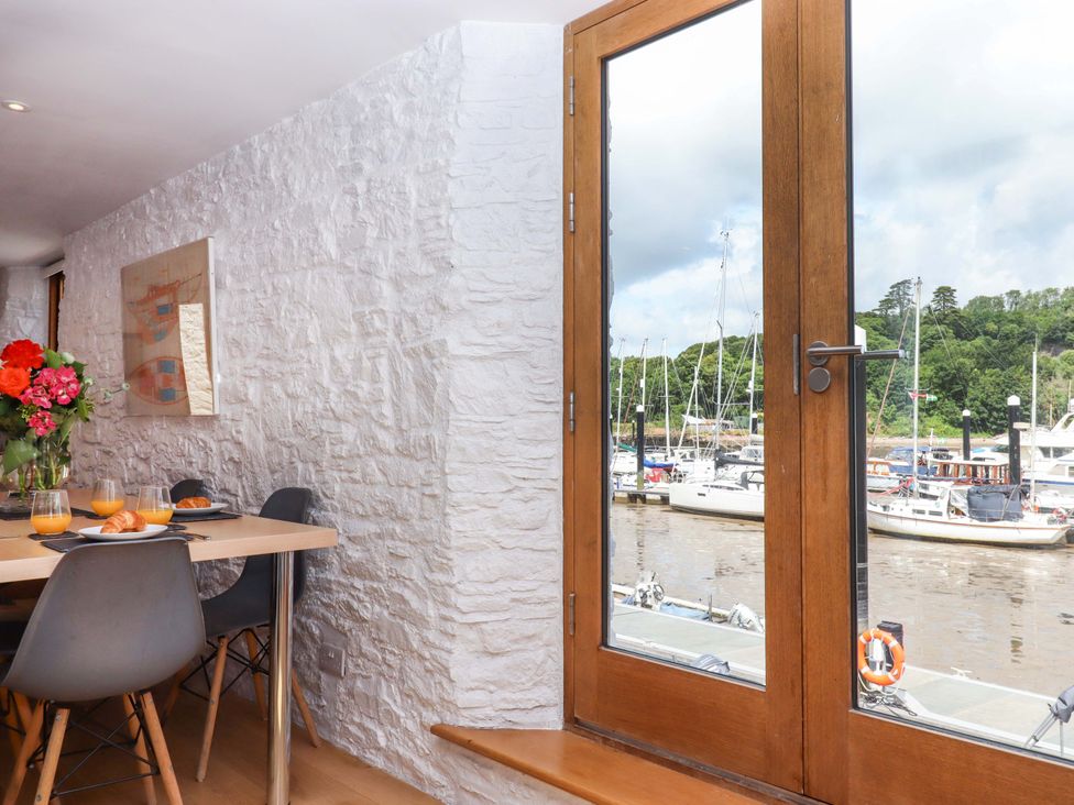 A dining room with a table and view of the marina at Dolphin Cottage in Brixham