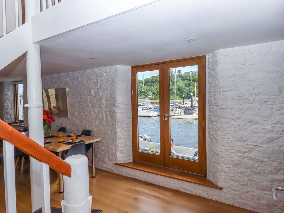 A dining room with glass doors and a view of the marina at Dolphin Cottage in Brixham