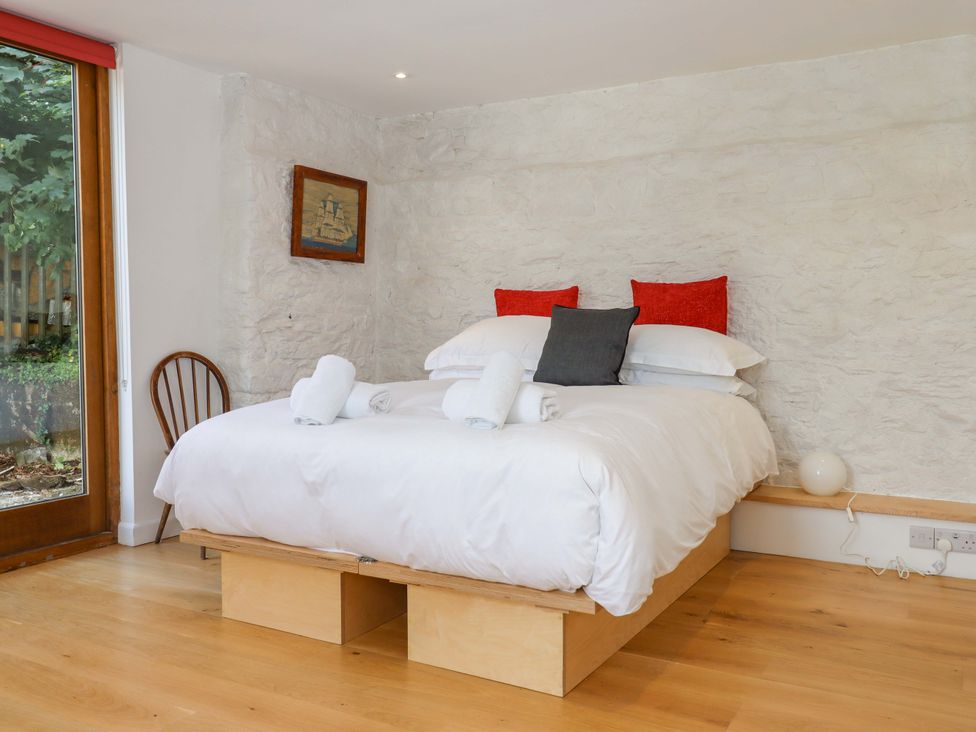 A bedroom with a bed and chair at Dolphin Cottage in Brixham