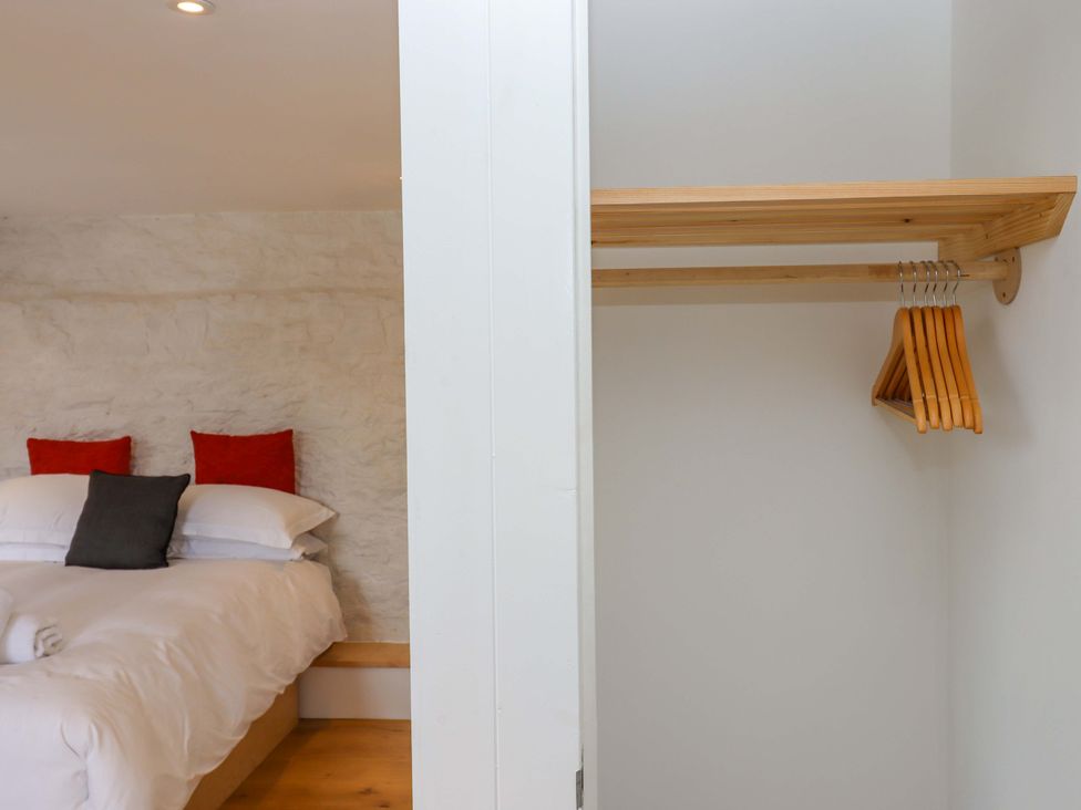 A bedroom with a bed and closet space at Dolphin Cottage in Brixham