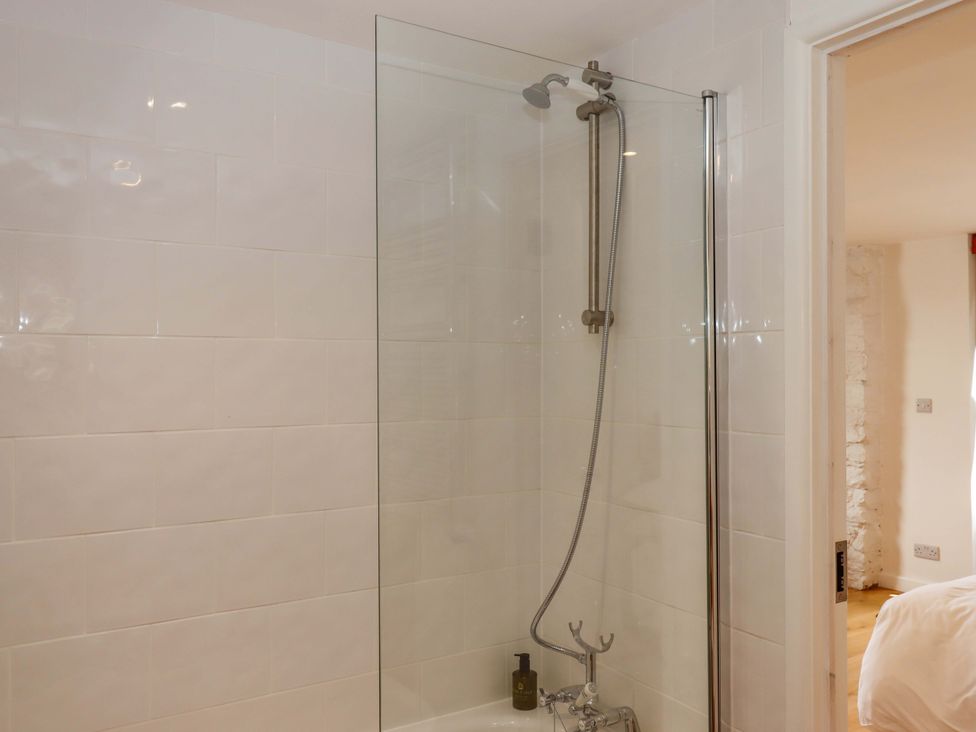 A shower with bathtub and wall tiles at Dolphin Cottage in Brixham