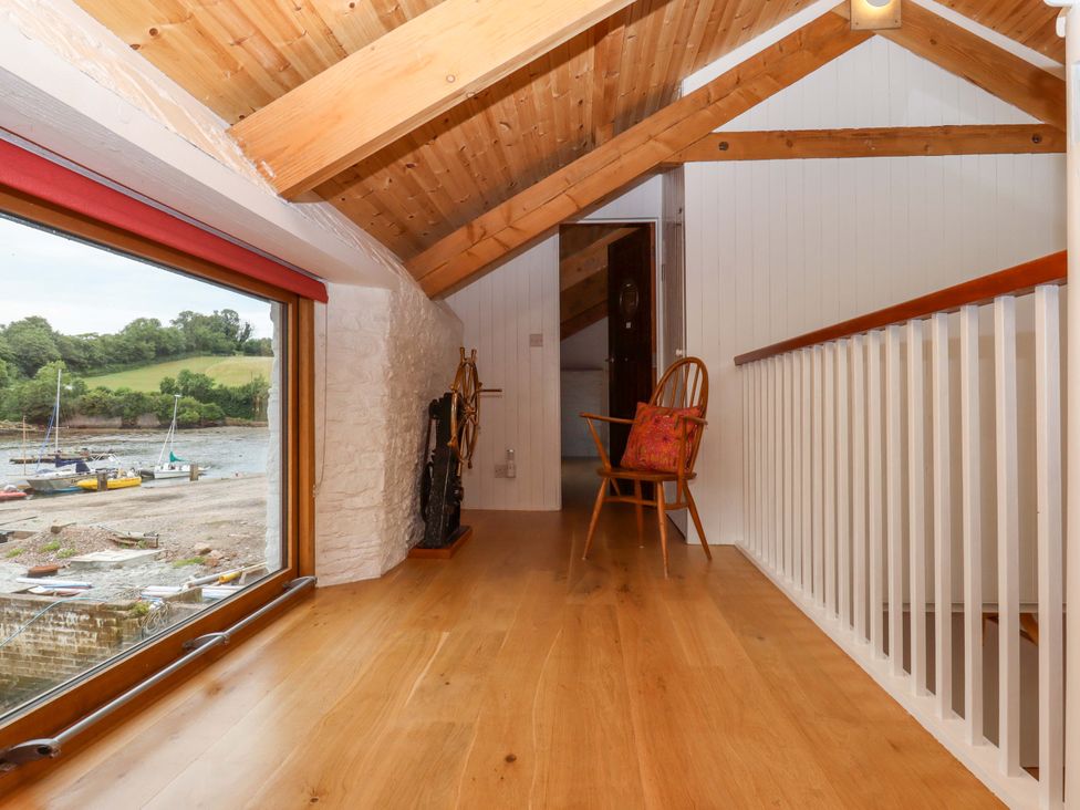 A hallway with a chair and window at Dolphin Cottage in Brixham