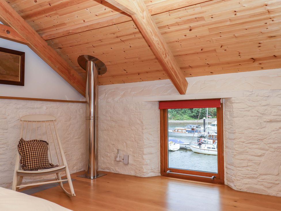 A bedroom with a rocking chair and a window overlooking the water at Dolphin Cottage Brixham
