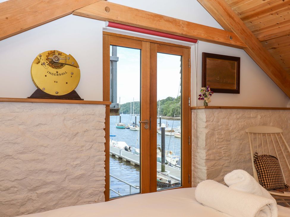 A bedroom with a view of boats through a window at Dolphin Cottage in Brixham