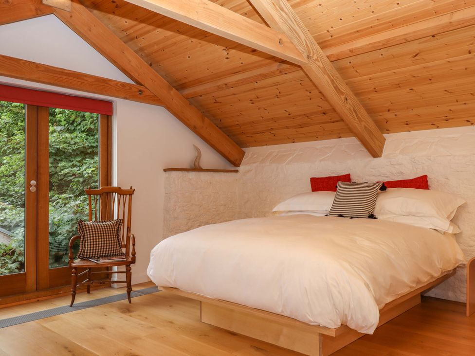 A bedroom with a bed and chair at Dolphin Cottage in Brixham