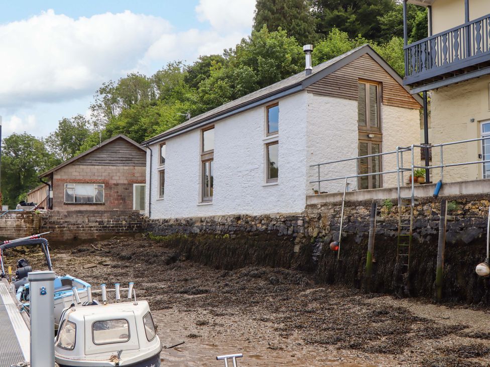 A house by the water with a boat near the shore at Dolphin Cottage in Brixham