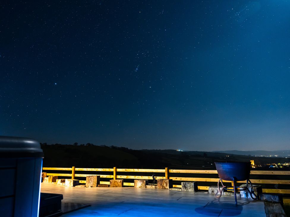 An outdoor area with a deck and chair under a starry night sky at Ceunant in Llanfihangel-y-Creuddyn near Aberystwyth