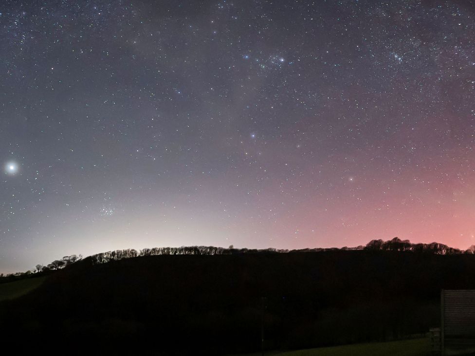 A night sky with stars and a silhouette of hills at Ceunant in Llanfihangel-y-Creuddyn near Aberystwyth