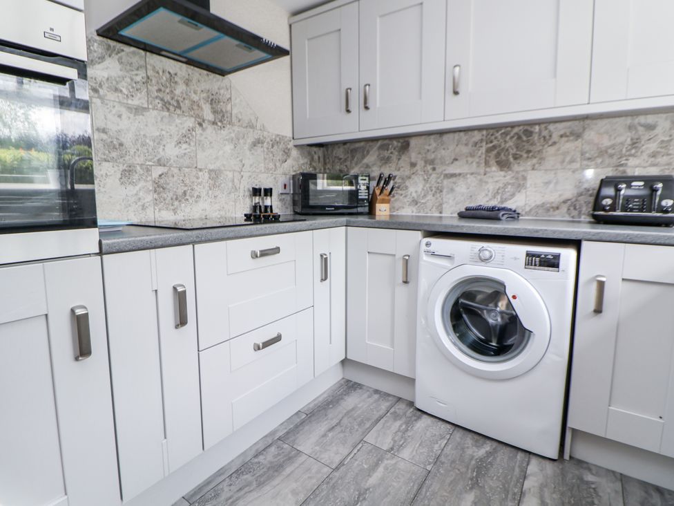A kitchen featuring a washing machine and microwave at Fern Cottage in Biddulph