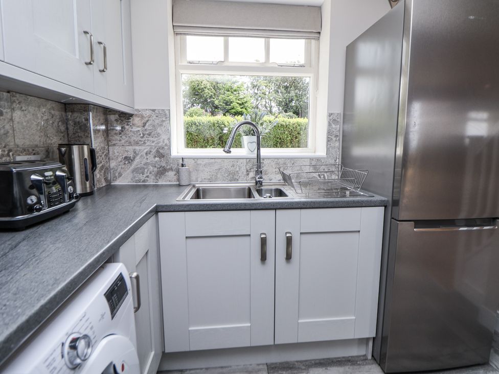 A kitchen with a sink and refrigerator at Fern Cottage in Biddulph
