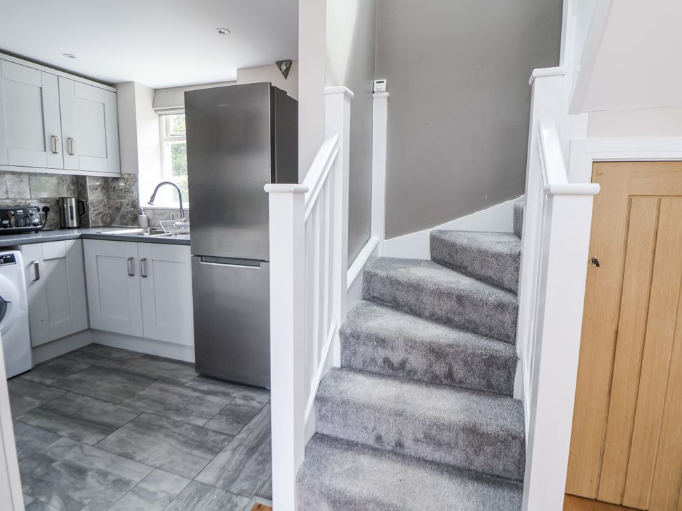 A kitchen with a refrigerator and a staircase at Fern Cottage in Biddulph