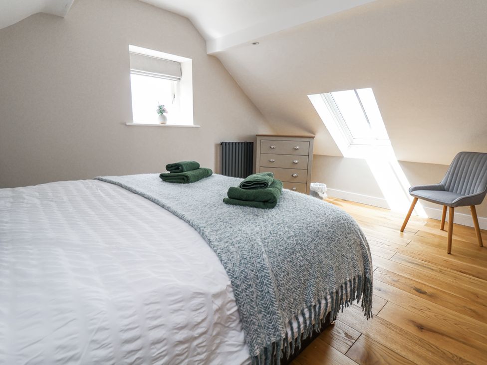 A bedroom with a bed and chair at Fern Cottage in Biddulph