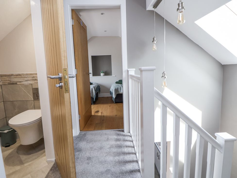 A hallway with a door and a view into a bedroom at Fern Cottage in Biddulph