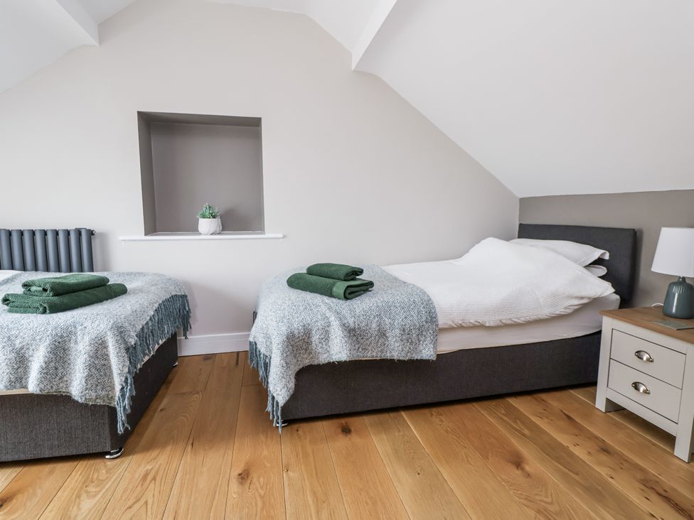 A bedroom with two beds and a side table at Fern Cottage in Biddulph