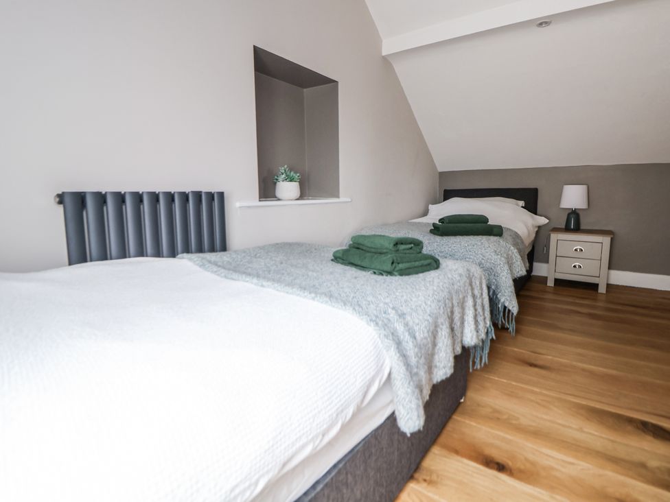 A bedroom with two beds and a bedside table at Fern Cottage in Biddulph