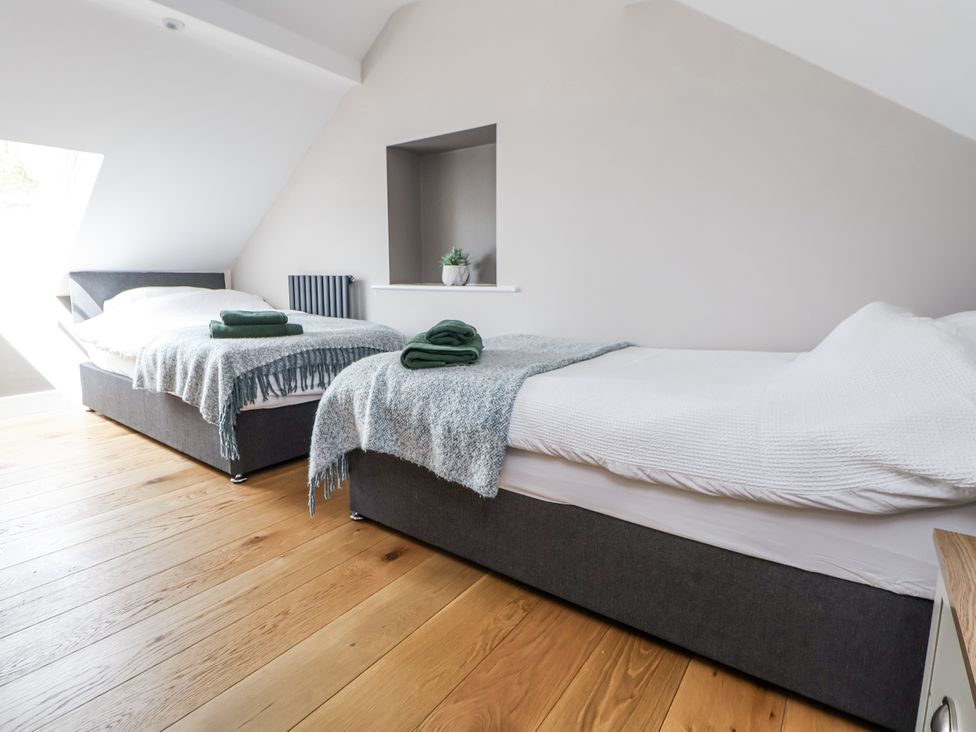 A bedroom with two beds and a window at Fern Cottage Biddulph