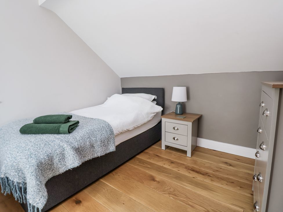 A bedroom with a bed and nightstand at Fern Cottage Biddulph