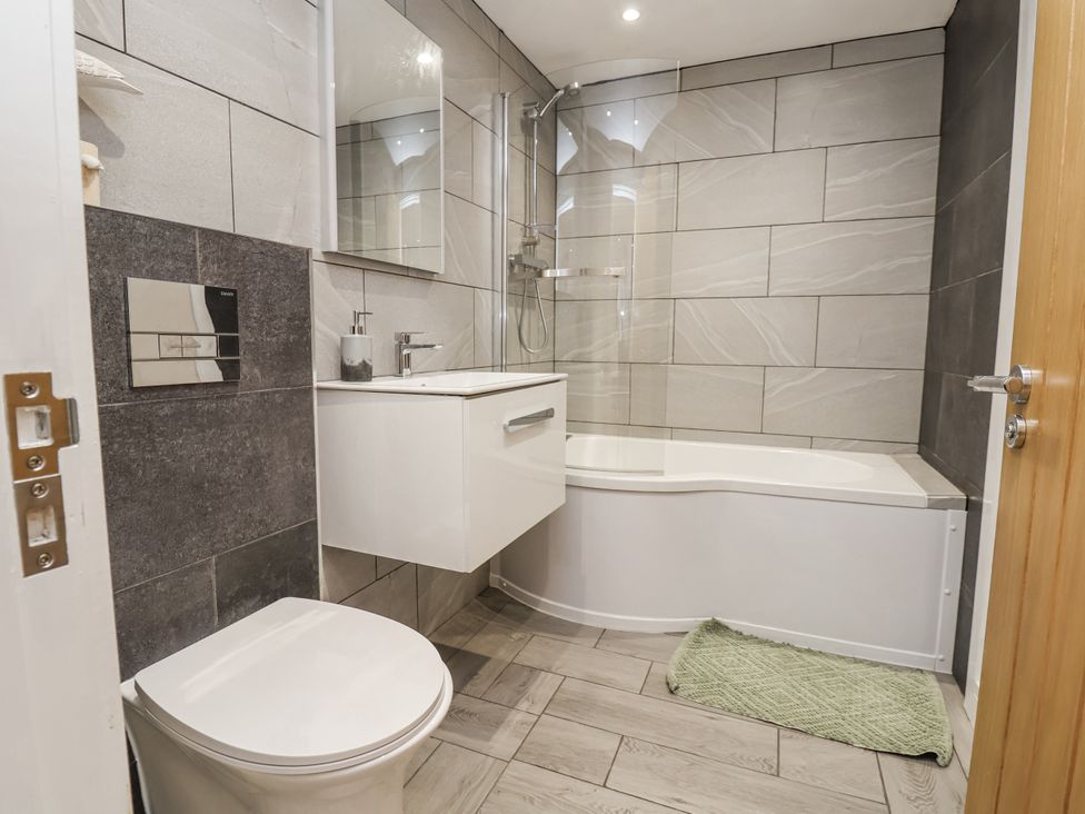 A bathroom with a bathtub, sink, and toilet at Fern Cottage in Biddulph