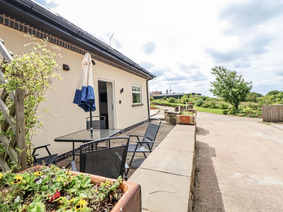 An outdoor seating area with a table and chairs at Fern Cottage in Biddulph