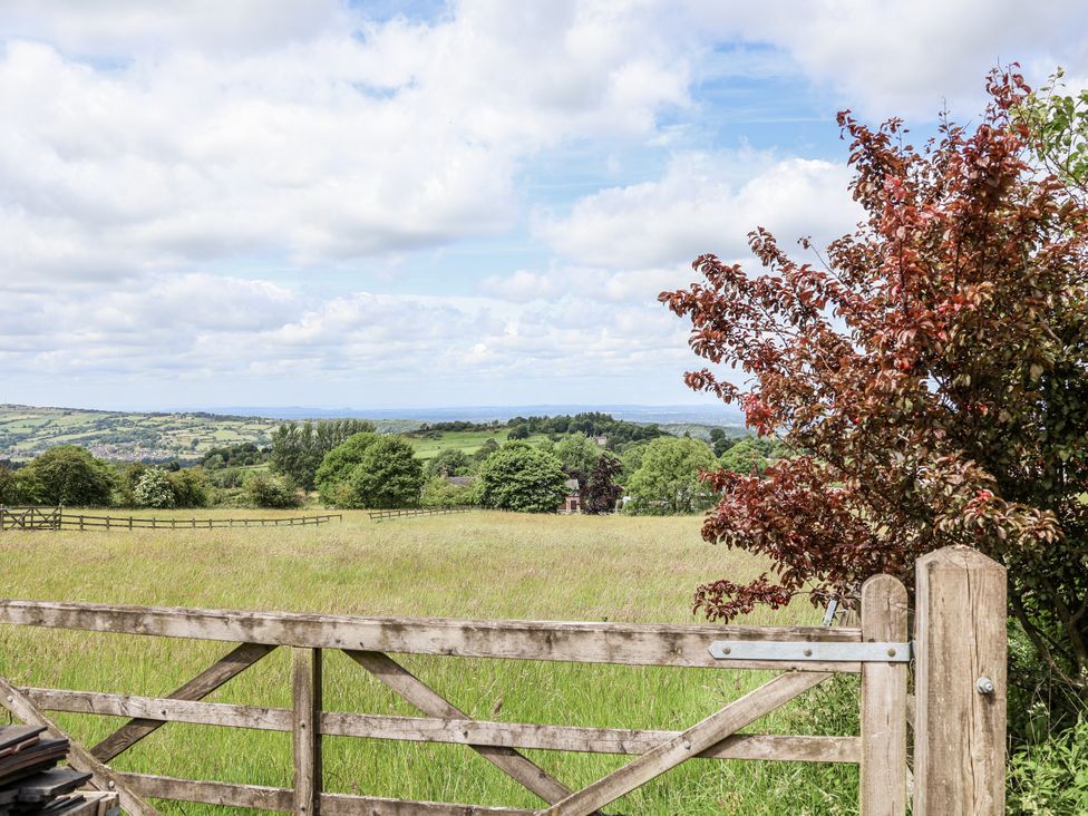 A view of a meadow with a wooden gate and trees at Fern Cottage in Biddulph